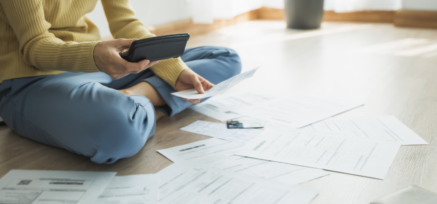 Pessoa sentada no chão a organizar documentos e recibos para pedido de crédito habitação